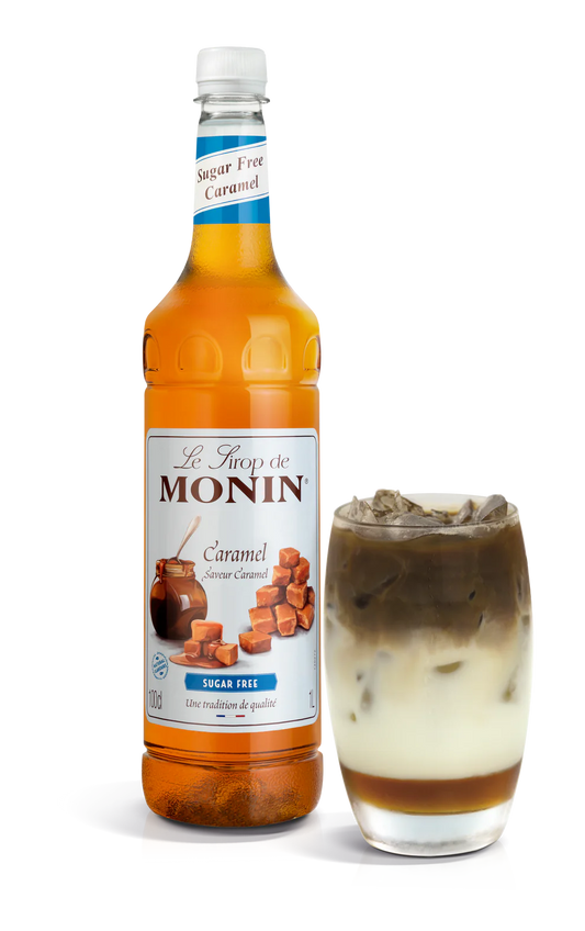 A bottle of Monin Sugar Free Caramel Syrup alongside a glass with syrup-drizzled dessert.