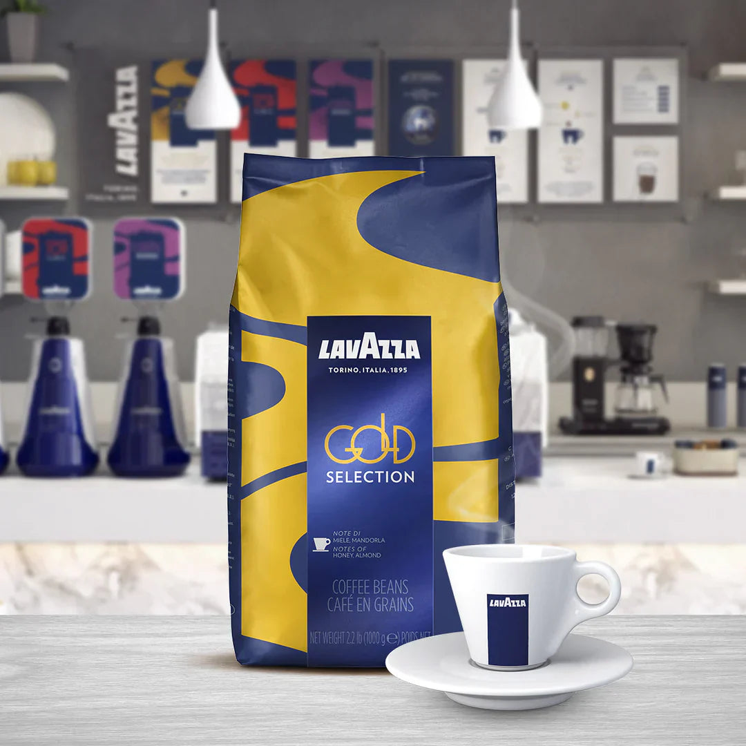 A package of Lavazza Gold Selection Coffee Beans displayed in front of a counter with various coffee-related items.