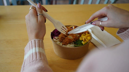 Lifestyle stock photo of hands using Go-Pak paper cutlery kitchen knives and fork over food bowl.